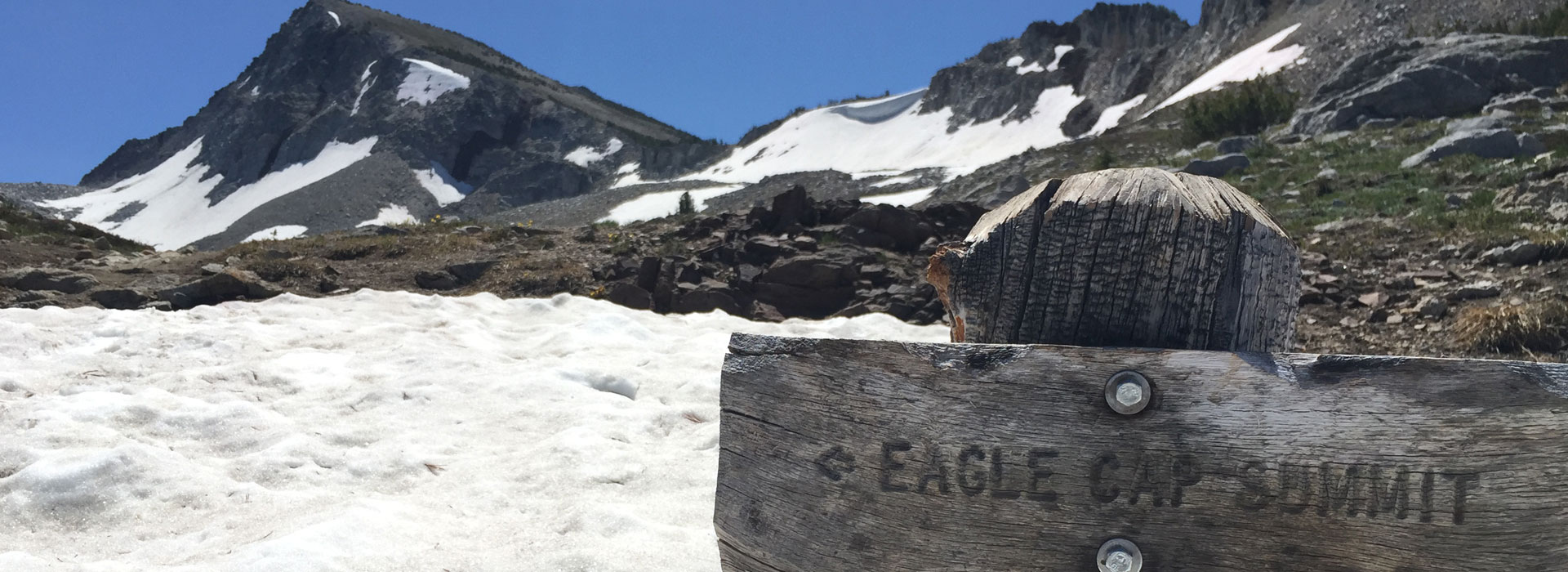 A wooden sign on the side of a mountain.